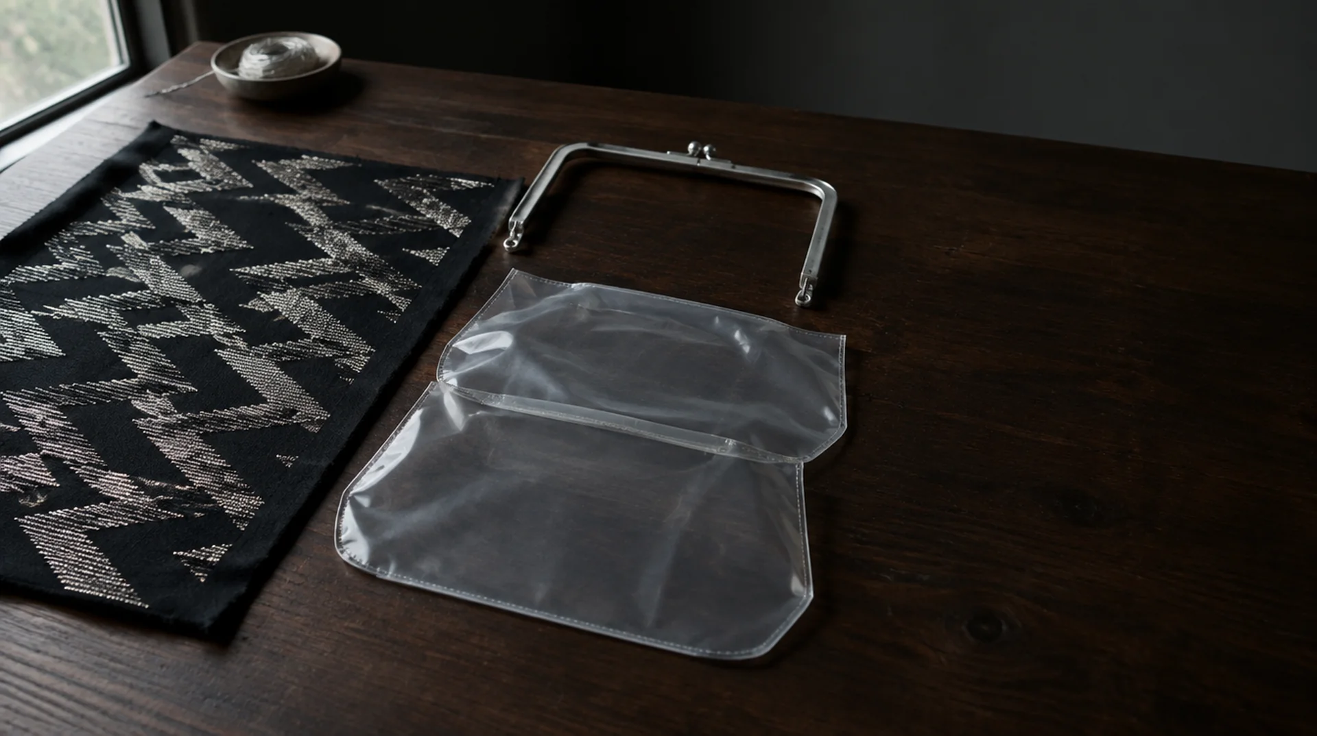 İşlemesi tamamlanmış kumaş, metal çanta kasası ve plastik kapak yan yana